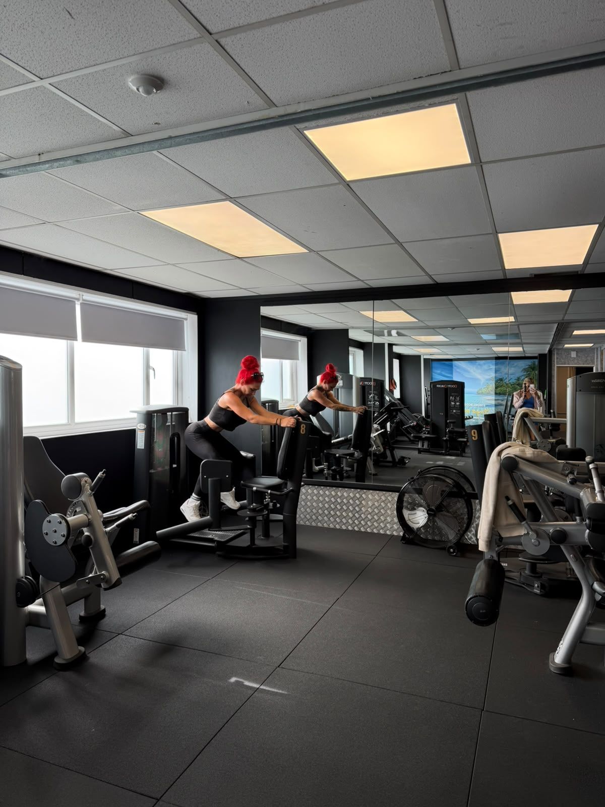 Members using resistance machines in a bright, mirrored training room.